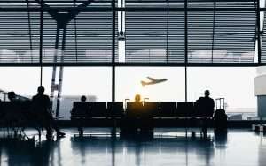 As companhias aéreas mais inseguras do mundo. Silhuetas de pessoas à espera nas portas de embarque de um avião.