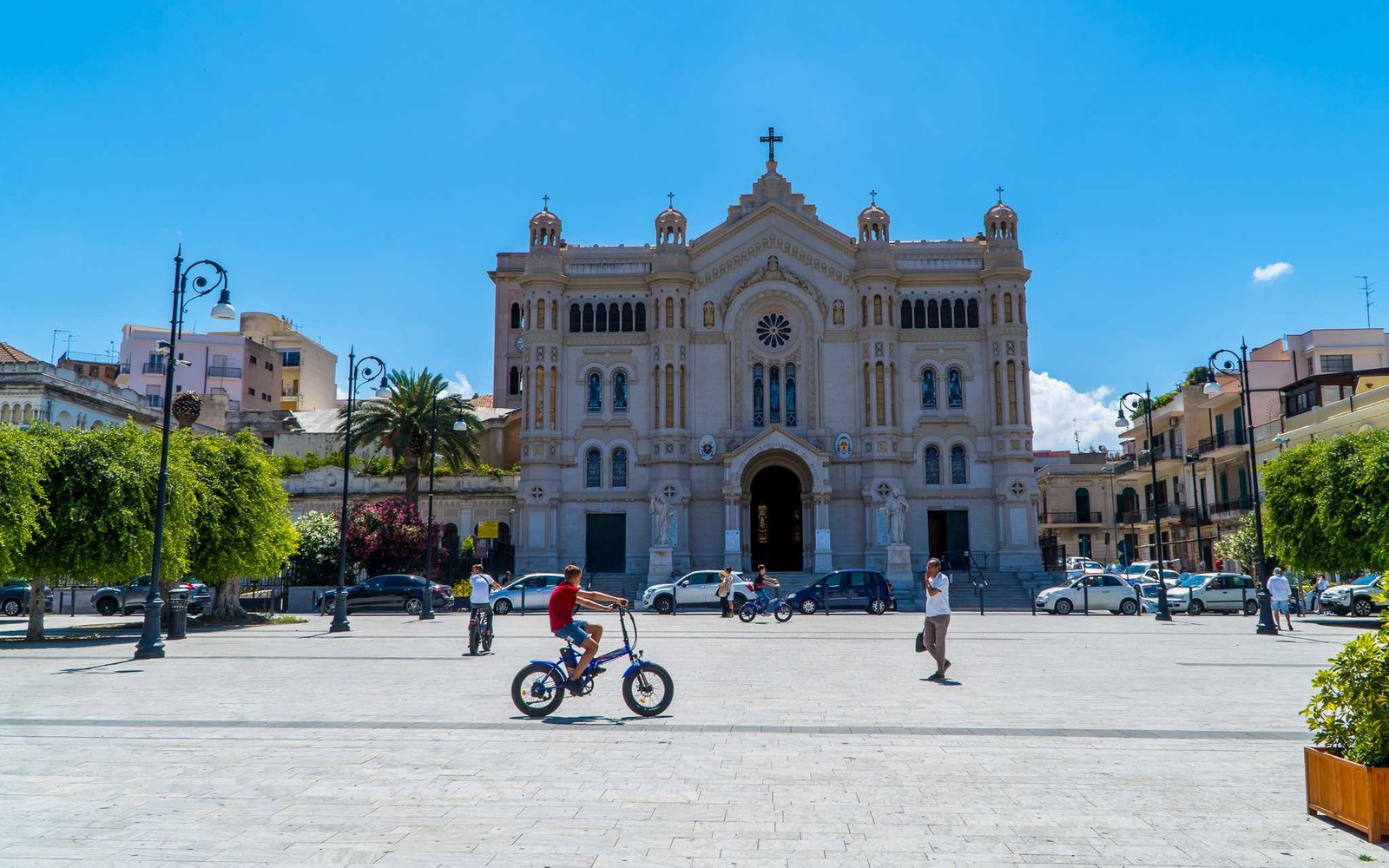 Cyclist and people walking in front of church in the centre of Reggio Calabria, in Italy, one of the countries to travel in 2025
