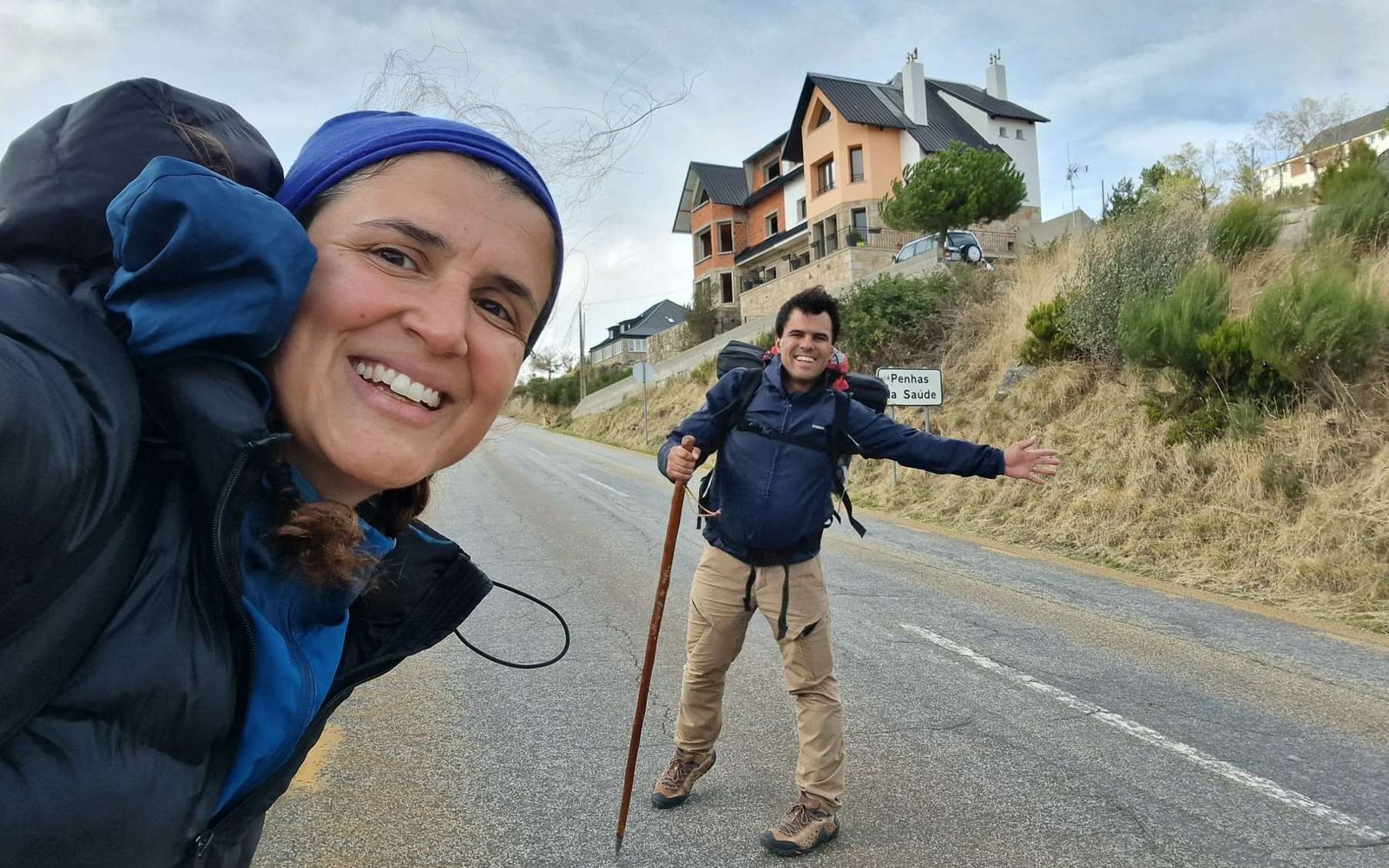 João Valente and his wife hiking during a motorhome travel journey in the Portuguese mountains, carrying backpacks and a walking stick.