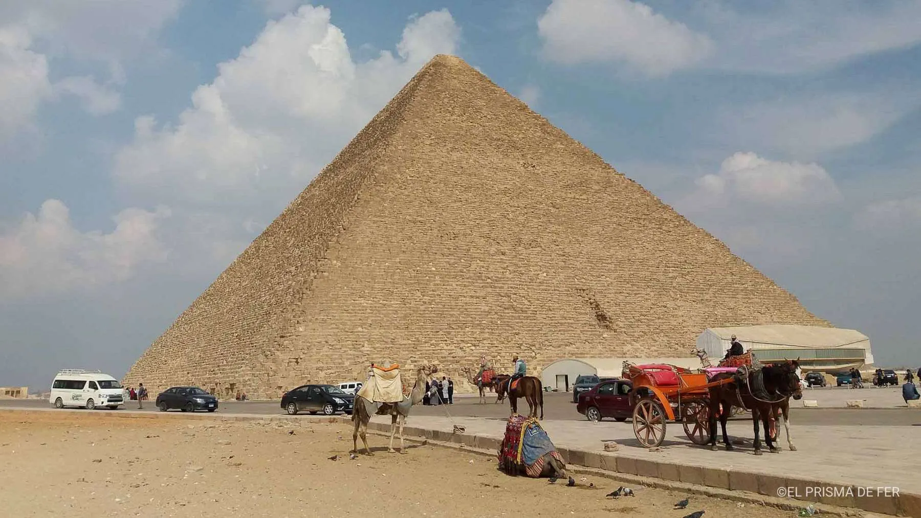 Impressive view of the Great Pyramid of Khufu in Giza, with camels and horse carriages in the foreground, capturing the authentic atmosphere around one of the greatest wonders of the ancient world.