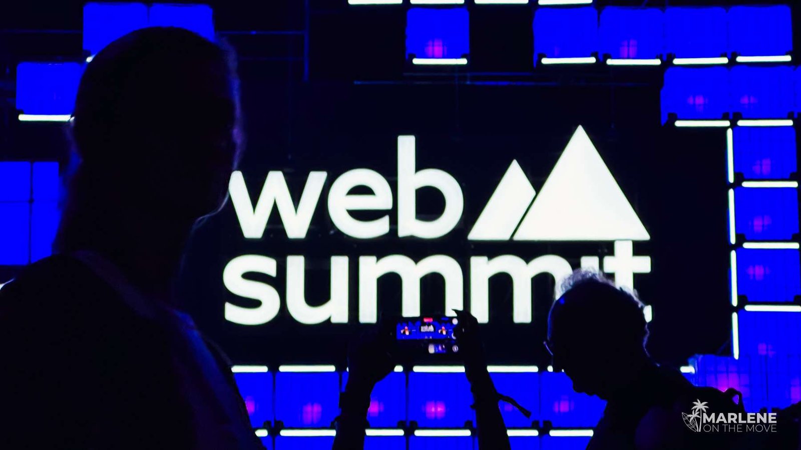 Palco principal do Web Summit com o logótipo iluminado e participantes a assistir às palestras sobre tecnologia e criação de conteúdo.