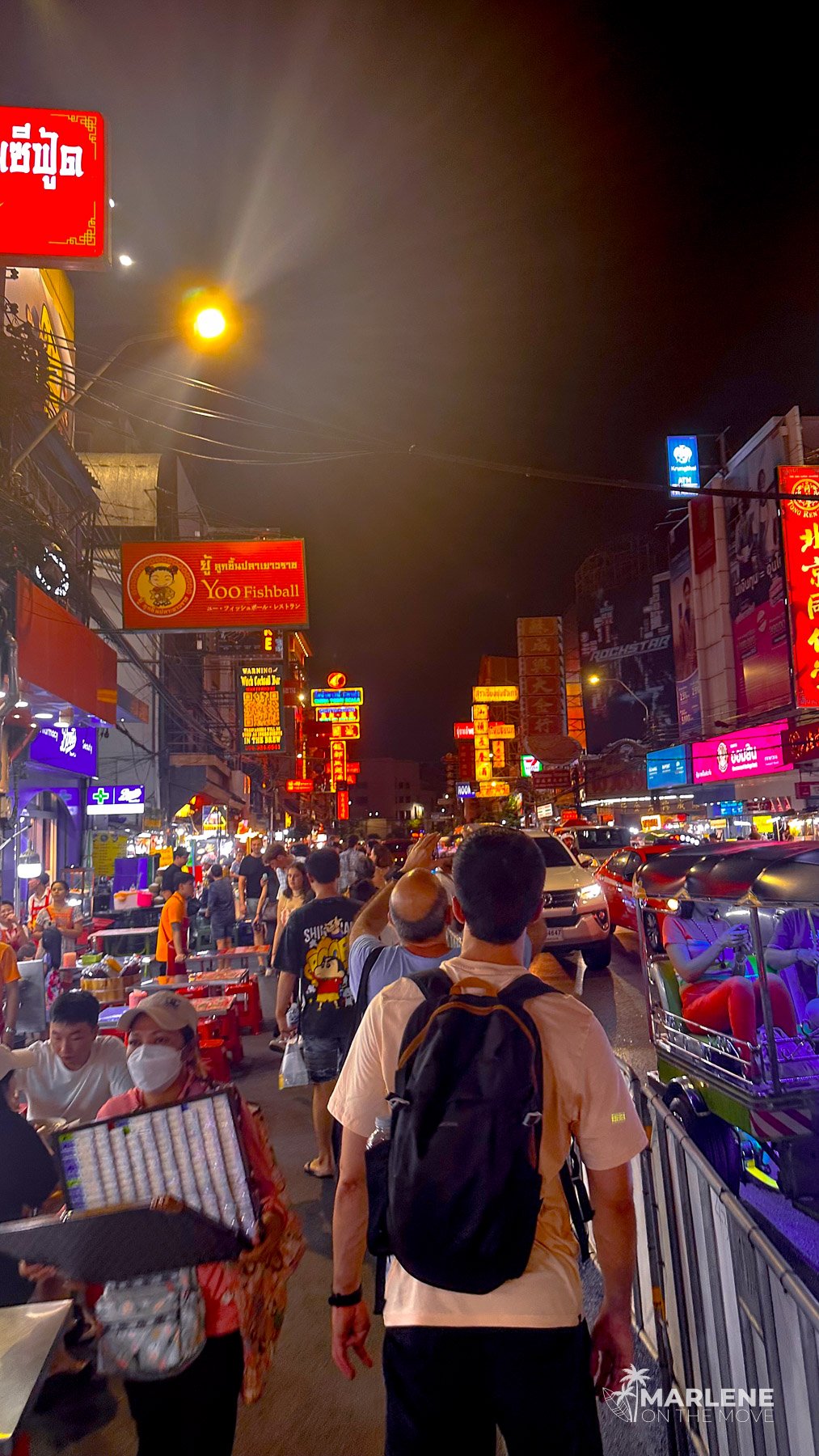 Caminhar pela Chinatown à noite, rodeado por luzes de néon, barracas de comida de rua e multidões.