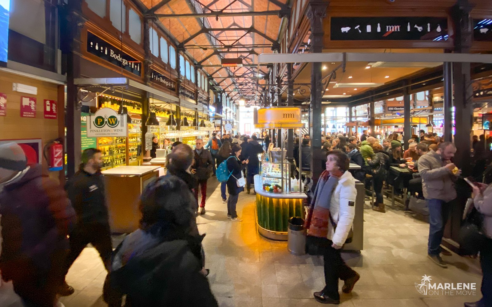 Interior of Mercado de San Miguel in Madrid with visitors enjoying tapas and drinks at the counters.