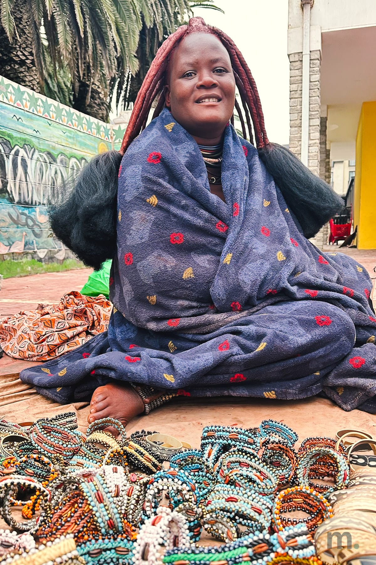 Himba woman at the Swakopmund craft market with beaded bracelets laid out in front of her