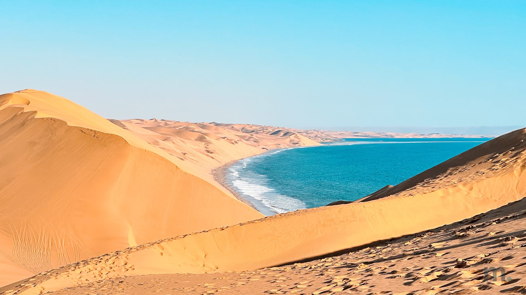 Swell breaking along the Namibian coast with the dune sea behind